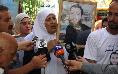 enant une photo de son fils grèviste de la faim, la mère de Hassan Safadi parle aux journalistes dans Naplouse le 28 juin 2012 - Photo : Ahmad Al-Bazz/ActiveStills 