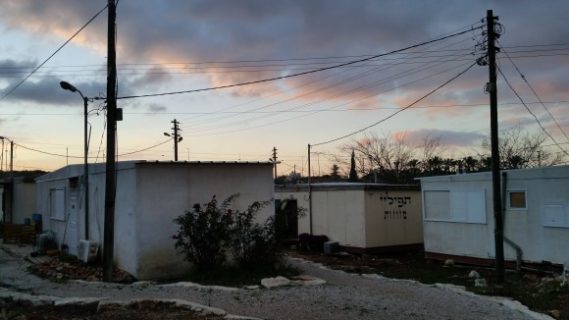 Des logements modulaires pour les nouveaux venus à la colonie d'Ofra, en Cisjordanie. Sur l'un d'eux, de la publicité pour des objets de culte, tels mezouzot et phylactères. (Photo : Philip Weiss)