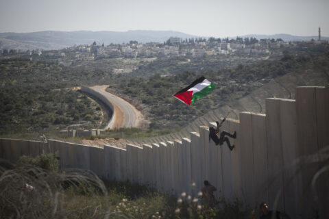 Février 2014. Un jeune Palestinien installe un drapeau en haut du mur d’Israël, lors d’une manifestation dans le village de Bilin, en Cisjordanie. (Photo : Oren Ziv / ActiveStills)