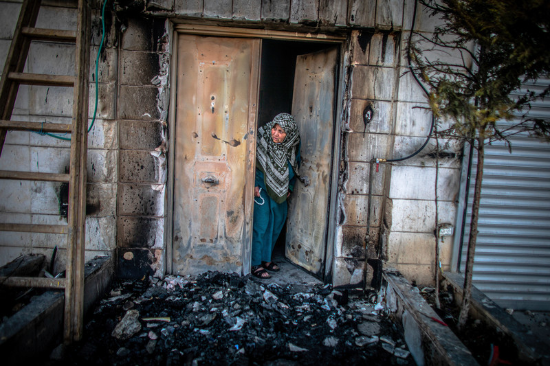 Une Palestinienne examine l’extérieur de sa porte incendié par des colons juifs à Huwwara, en Palestine occupée, le 26 février 2023