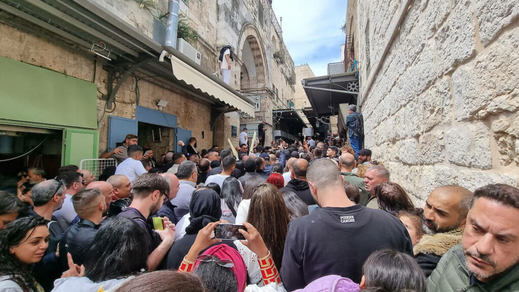 Le 15 avril 2023, des fidèles chrétiens attendent derrière une barrière dressée par les forces de sécurité israéliennes et bloquant la voie vers l’église du Saint-Sépulcre de Jérusalem, lors des célébrations du samedi de Pâques de l’Église orthodoxe chrétienne. 