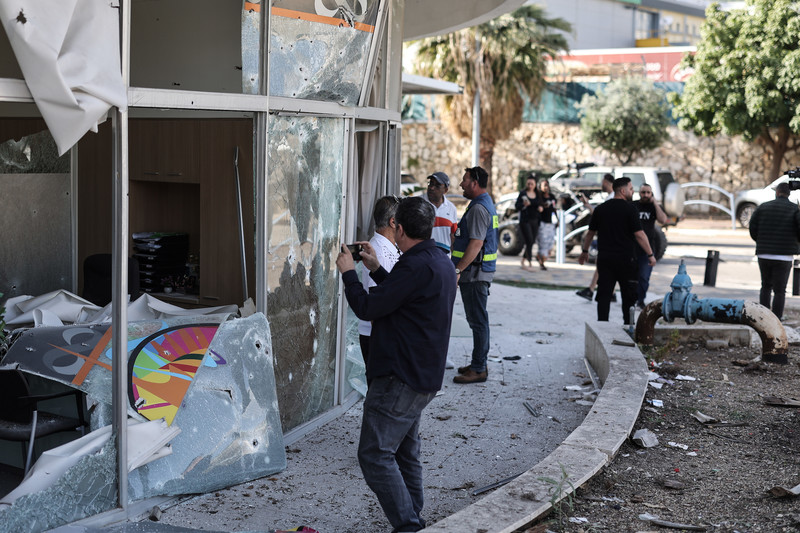 Shlomi, une ville du nord d’Israël. Des badauds examinent les dégâts infligés à une banque après qu’elle a été frappée par une roquette interceptée, lancée à partir du Liban.