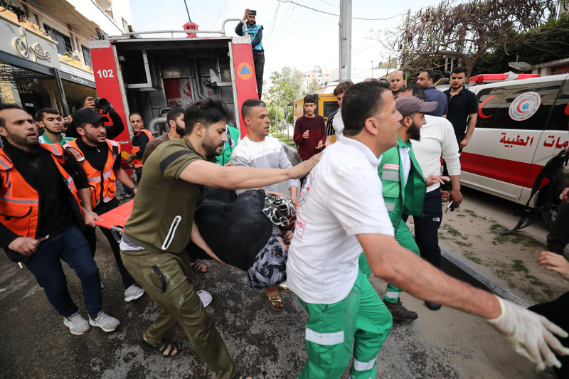 12 mai. Des Palestiniens évacuent une personne blessée après qu’un immeuble à appartements a été ciblé par Israël à Gaza.