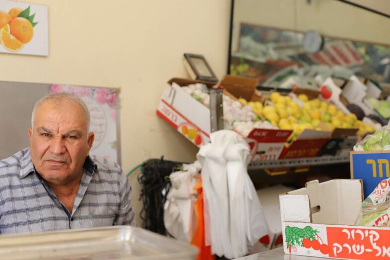Mohammad al-Amir est assis dans son magasin familial de fruits et légumes. (Photo : Malik Hamamra / Mondoweiss) Camp de réfugiés d’Aida, Cisjordanie occupée, mai 2023. 
