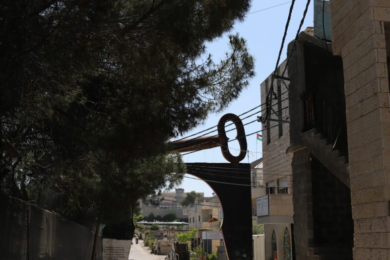 La Clé du Retour est une structure plus grande que nature qui se trouve à l’entrée du camp d’Aida. Posée au sommet d’une structure censée ressembler à un ancien cadenas, la clef est un symbole de l’espoir tenace des réfugiés palestiniens de retourner un jour dans leurs terres d’origine. (Photo : Malik Hamamra / Mondoweiss) Camp de réfugiés d’Aida, Cisjordanie occupée, mai 2023.