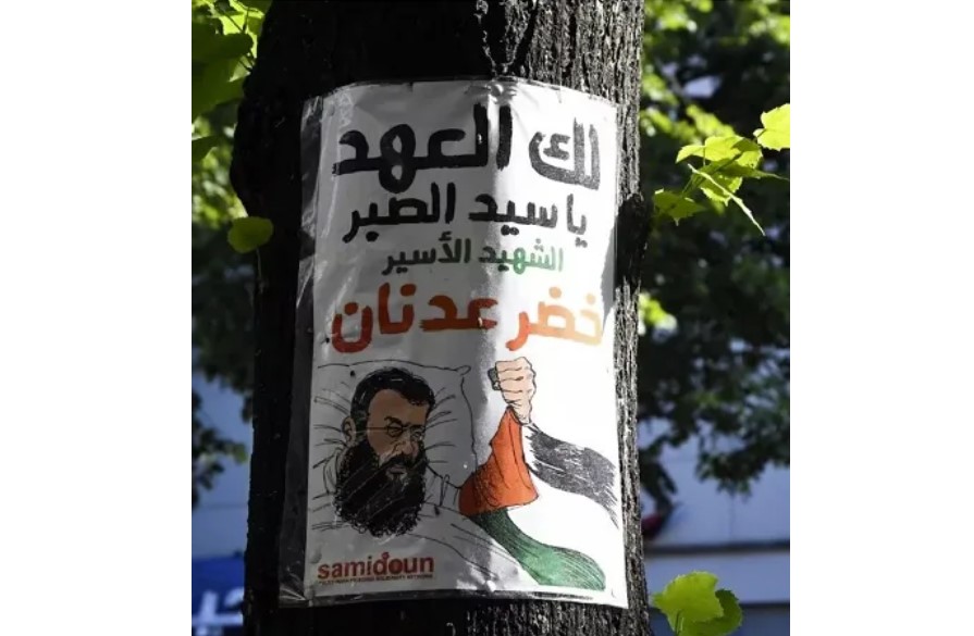 Affiche de Samidoun placardée sur un arbre de l’arrondissement de Neukölln, à Berlin, et représentant le prisonnier martyr Khader Adnan accompagné d’une référence à ses légendaires grèves de la faim durant ses années de captivité dans les prisons israéliennes : « Nous te le promettons, ô maître de l’endurance. » (Photo : Samidoun)