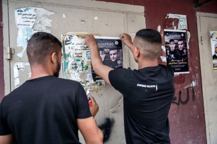 Deux jeunes placardent ses affiches de deux Palestiniens abattus par l’armée israélienne, Hamza Kharyoush et Samer al-Shafei, tous deux 22 ans, tués à Tulkarem au début mai, la veille du démarrage de l’exposition d’Ahmad al-Bazz. (Photo : Anne Paq)