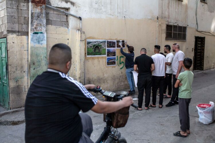 Une petite foule s’assemble autour d’Ahmad al-Bazz au moment où il est occupé à fixer ses photos dans le camp de Far’a. (Photo : Anne Paq)