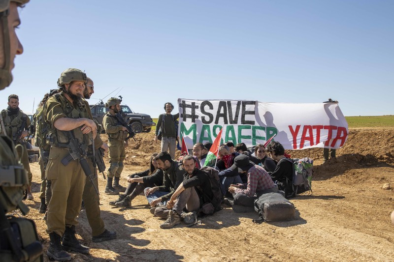 Des activistes israéliens et internationaux sont entourés de soldats alors qu’ils tentent de bloquer un check-point militaire à Masafer Yatta, en février 2023.