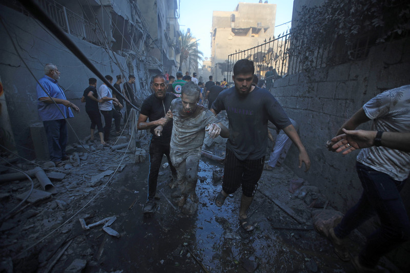 11 octobre 2023. Des Palestiniens aident à l’évacuation d’un homme blessé après une frappe aérienne israélienne sur Gaza