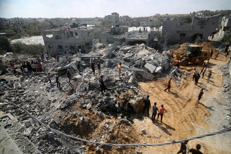 7 octobre 2023. Des Palestiniens fouillent les décombres des immeubles détruits par une frappe israélienne à Rafa, dans le sud de Gaza. 