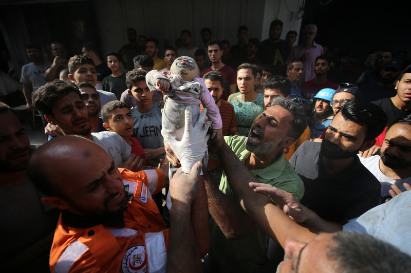 Un Palestinien, que l’on peut également voir dans la vidéo ci-dessous, porte le corps d’un bébé tué lors d’une attaque israélienne contre le camp de réfugiés d’al-Shati (Beach Camp) à Gaza. 
