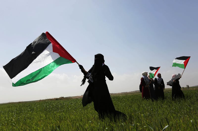 29 mars 2018, à l’est de la ville de Gaza. Une Palestinienne agite un drapeau palestinien devant elle en guise de protestation. La scène se déroule dans un village de tentes à proximité de la frontière entre Gaza et Israël. Ces personnes exigent de pouvoir retourner dans leur patrie. 