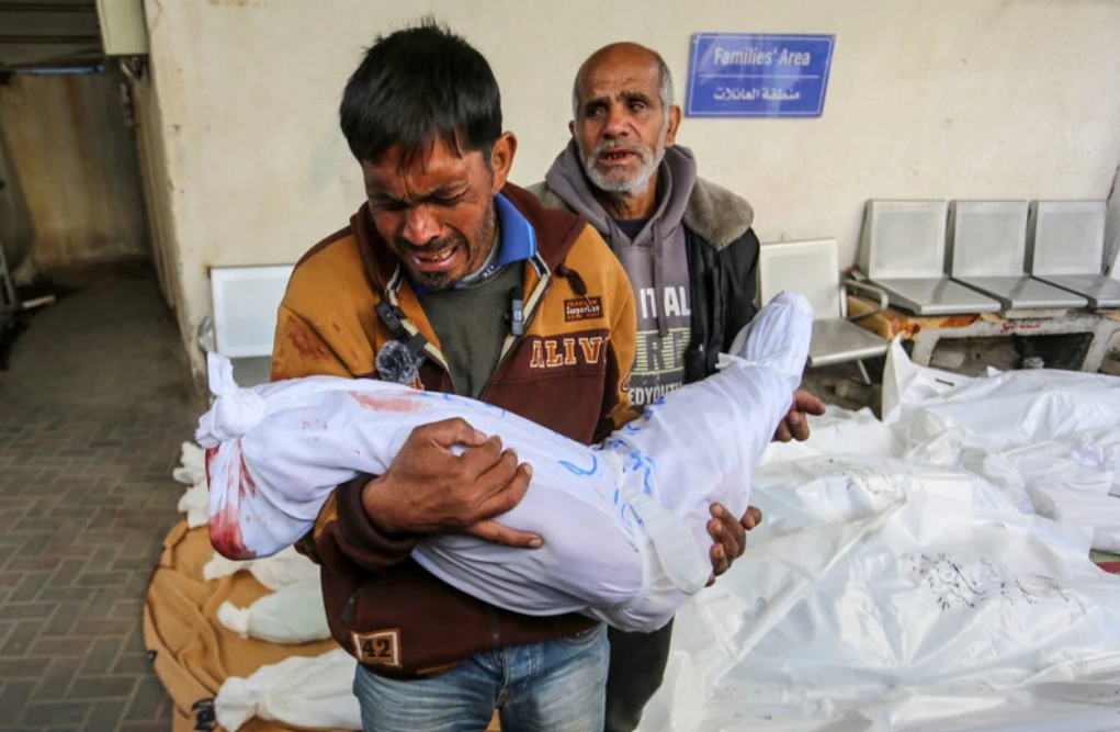 12 décembre 2023. Un Palestinien porte dans ses bras un membre de sa famille tué par une frappe israélienne contre l’hôpital al-Najjar, à Rafah, dans le sud de la bande de Gaza. 