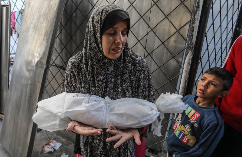 19 décembre 2023. Une Palestinienne porte le corps enveloppé de son enfant tué par une frappe israélienne à Rafah, dans le sud de Gaza. 