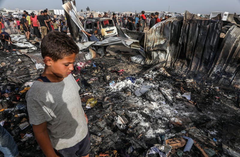 27 mai 2024. Un petit Palestinien examine les dégâts après qu'une frappe israélienne sur les tentes hébergeant des personnes déplacées s'est soldée par des douzaines de morts et de blessés à Rafah, dans le sud de Gaza. 