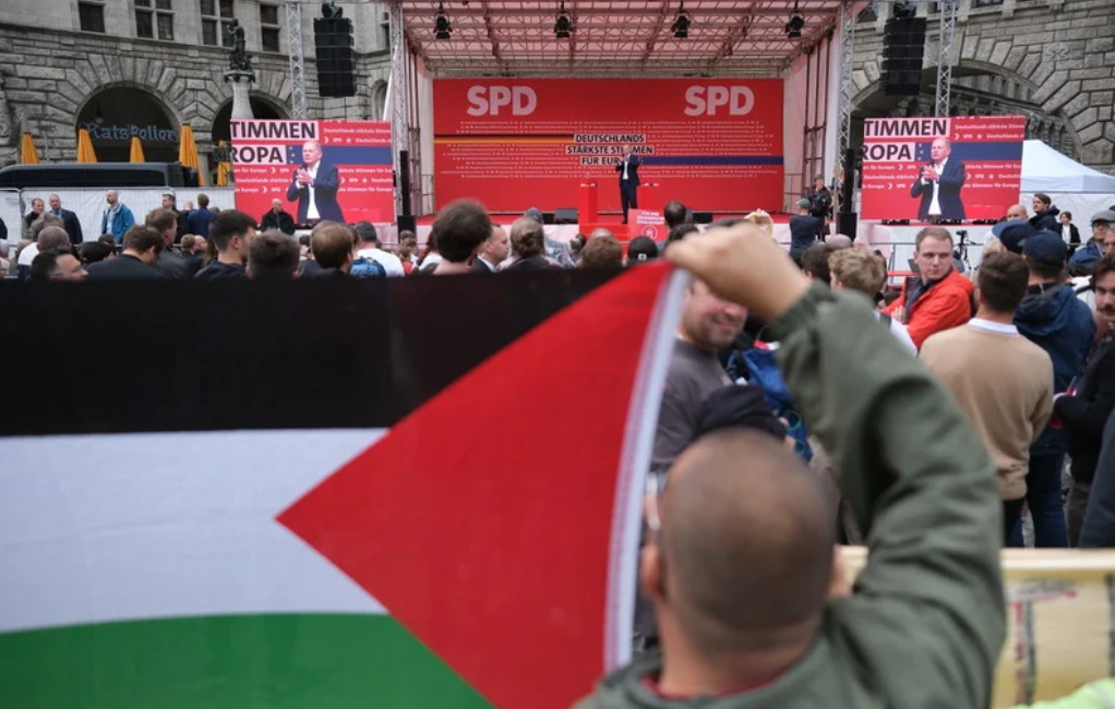 Leipzig, Allemagne, 1er juin 2024. Un manifestant anti-génocide agite un drapeau palestinien au moment où le chancelier allemand Olaf Scholz prend la parole lors d'un rassemblement en vue des élections au Parlement européen. 