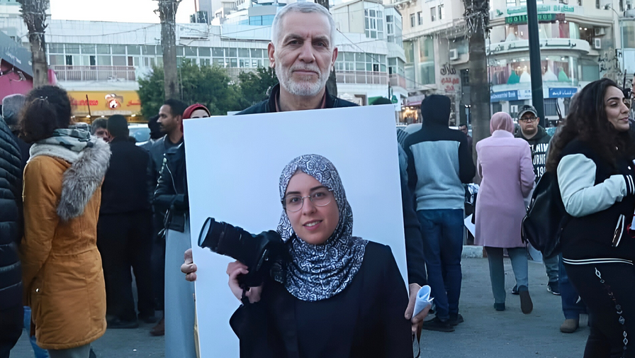 Jamal Al Taweel, portant un portrait de sa fille lors d’un rassemblement, avant qu’il ne soit à nouveau arrêté.