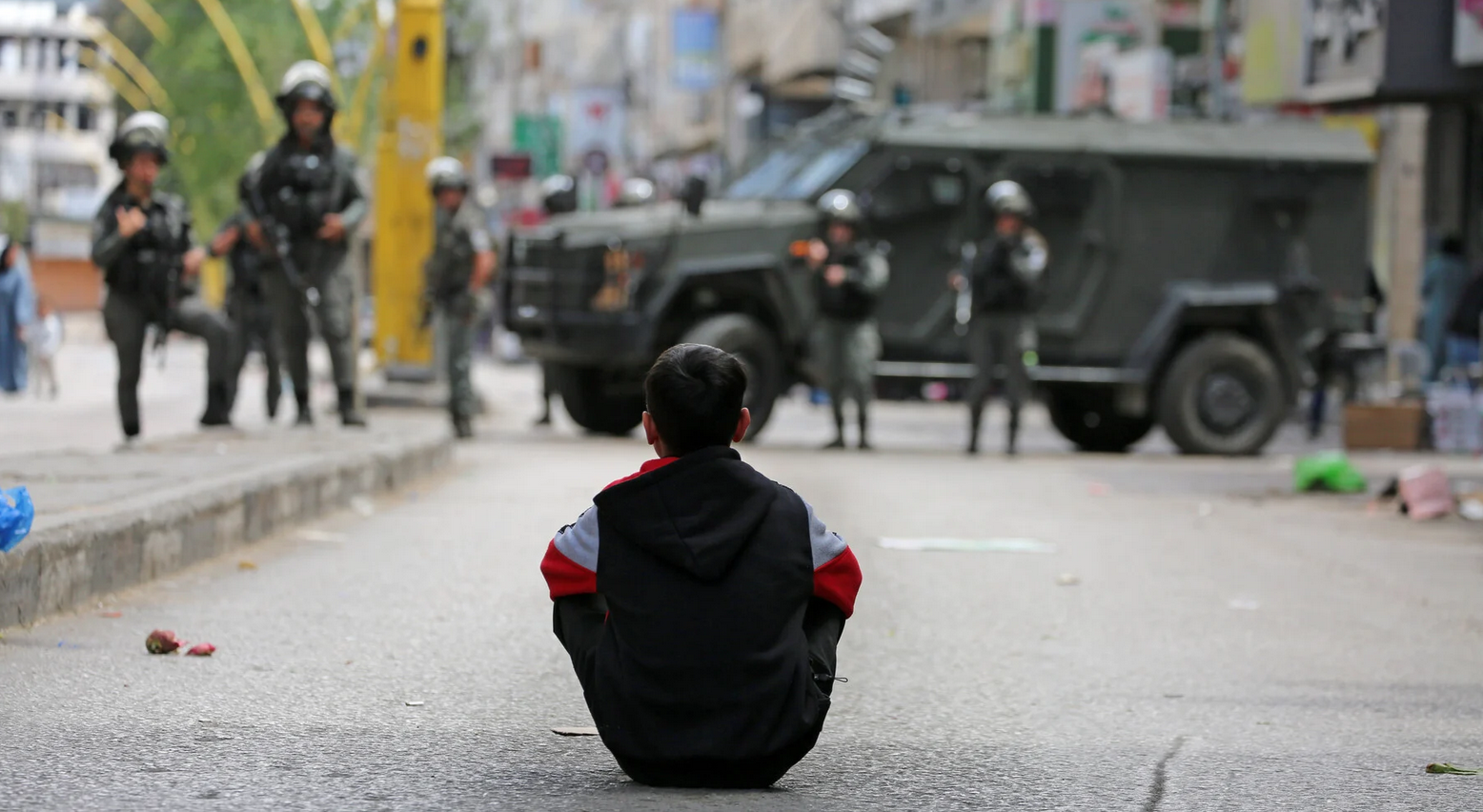 16 avril. Un enfant palestinien assis en face de soldats israéliens au moment où ils envahissent le centre de Hébron, dans le sud de la Cisjordanie, afin de garder des colons qui se livrent à des célébrations près d'une tombe ancienne lors de la fête de la Pâque.